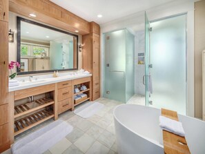 Une salle de bain moderne avec un grand miroir, un meuble-lavabo en bois, une baignoire et une douche à parois de verre.