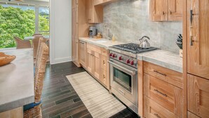 Une cuisine moderne avec des meubles en bois, une cuisinière à gaz et un four encastré.