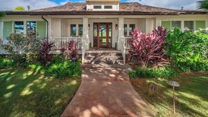 A two-story house with a front porch, a driveway, and a well-maintained garden. - Golf Course View | Resort Amenities | Chef’s Kitchen (Koloa)