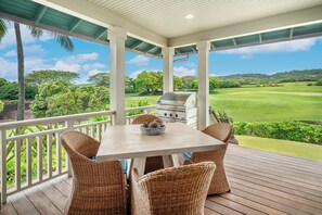 Un espace extérieur abrité, doté d’une table et de chaises en osier, avec vue sur un terrain de golf.