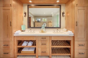 Une salle de bain moderne avec des meubles en bois, un grand miroir et un double vasque.