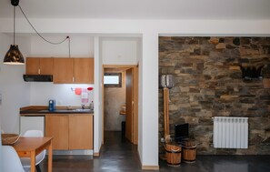 A modern kitchen with wooden cabinets, a built-in oven, and a stone wall.