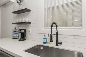 A kitchen with a stainless steel sink, a coffee maker, and two soap bottles.