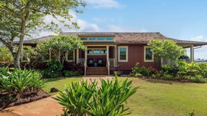 A two-story house with a front porch, surrounded by a well-maintained garden with various plants and a lawn.