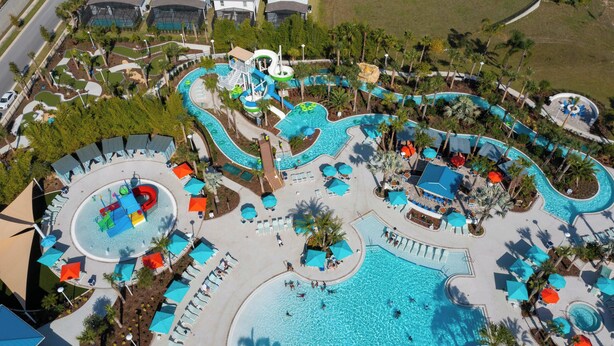 Eine Vogelperspektive zeigt einen luxuriösen Urlaubsort mit mehreren Schwimmbecken, Wasserrutschen und Liegestühlen.