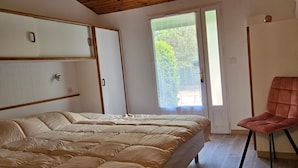 Une chambre comprenant un lit, une chaise, une armoire et une porte donnant sur un espace extérieur.