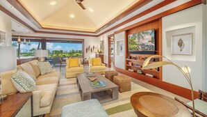 A spacious living room with a large TV, comfortable seating, and a view of the outdoors.