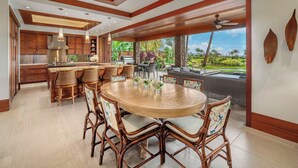 A spacious kitchen with wooden cabinets and a large island, connected to an outdoor dining area with wicker chairs and a round table.