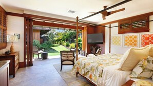 Ein Schlafzimmer mit einem Bett, einem Sessel, einem Schreibtisch und einem Fernseher. Ein Fenster und eine Tür führen zu einem Balkon.