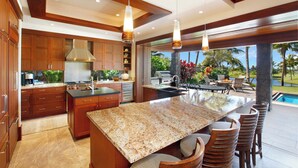 Eine moderne Küche mit Granit-Arbeitsplatten, Holzschränken und einer großen Kücheninsel mit Barhocker.