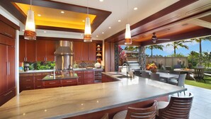 A modern kitchen with a large island, wooden cabinets, and pendant lighting. - Ocean Views | Plunge Pool & Fire Pit | Villa + Guesthouse (Koloa)