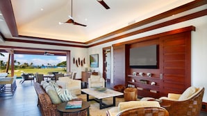 Uma sala de estar ampla, com uma televisão grande, assentos confortáveis e vista para o exterior.