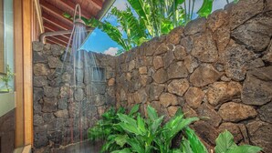 A stone wall with a water feature and lush greenery. - Ocean Views | Resort Amenities | Plunge Pool & Guesthouse (Koloa)