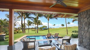 Un espacio exterior cubierto con mobiliario de mimbre, una piscina y vistas a un campo de golf.