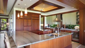 Una cocina moderna con una isla grande, armarios de madera e iluminación colgante.