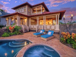 A two-story house with a large porch, a swimming pool, and a hot tub.