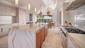 Una cucina moderna con isola in marmo, luci a sospensione e vista sull'esterno.