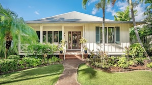 A single-story house with a white exterior, green shutters, and a covered porch. - Resort Amenities | Firepit & Outdoor Shower (Koloa)