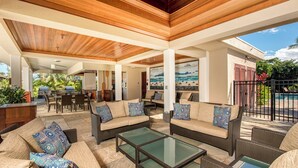An outdoor patio with wicker furniture, a glass-top coffee table, and a view of the backyard. - Mauna Lani Point J101 - Enhanced Comfort & Cleanliness | Professionally Managed (Kamuela)
