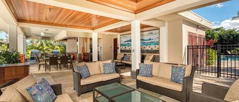 An outdoor patio with wicker furniture, a glass-top coffee table, and a view of the backyard.