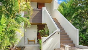 A modern house with a concrete staircase leading to a wooden door. - *CoralTree Managed* Ground Floor Ocean & Golf Views - Mauna Lani Point A107 (Kamuela)