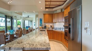 Una cocina moderna con encimeras de granito, armarios de madera y electrodomésticos de acero inoxidable.