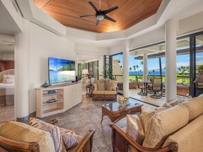 A spacious living area with a large flat-screen TV, comfortable seating, and a view of the ocean. - *CoralTree Managed* Ocean View on Top-Rated Golf Course | Mauna Lani Point B201 (Kamuela)