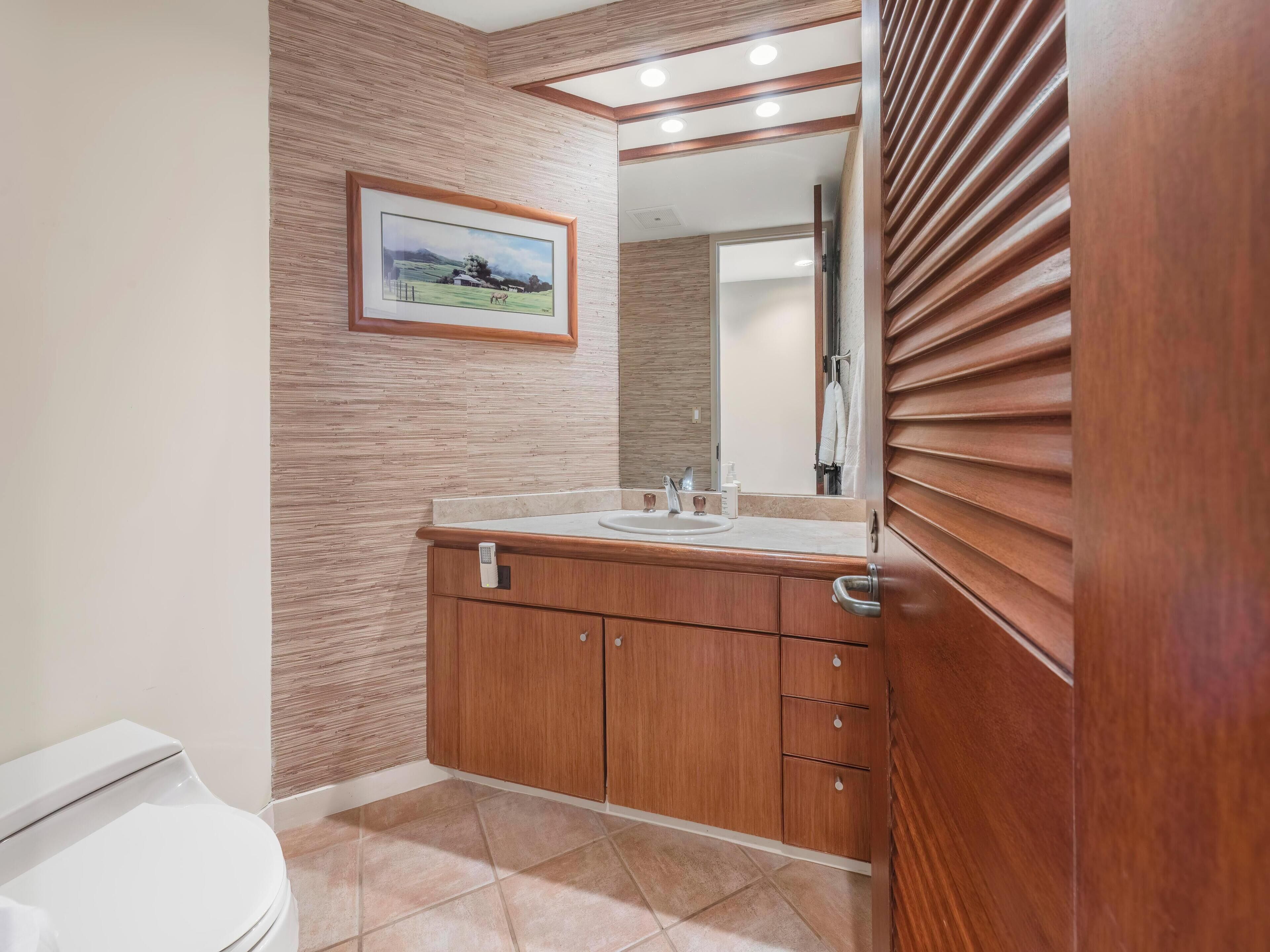 A bathroom with a wooden vanity, a sink, and a toilet.