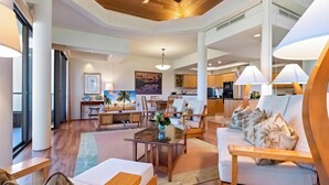 A spacious living area with a wooden ceiling, a dining table, and a sofa with palm-patterned cushions.