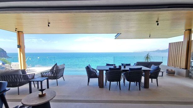 A terrace with a view of the sea, furnished with tables and chairs, and a wooden ceiling. - Iyari Luxury Villa: 4BR, Private Pool & Premier Access (Punta Mita)