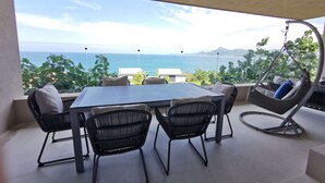 A terrace with a table and chairs, a hanging chair, and a view of the sea. - Iyari Luxury Villa: 4BR, Private Pool & Premier Access (Punta Mita)