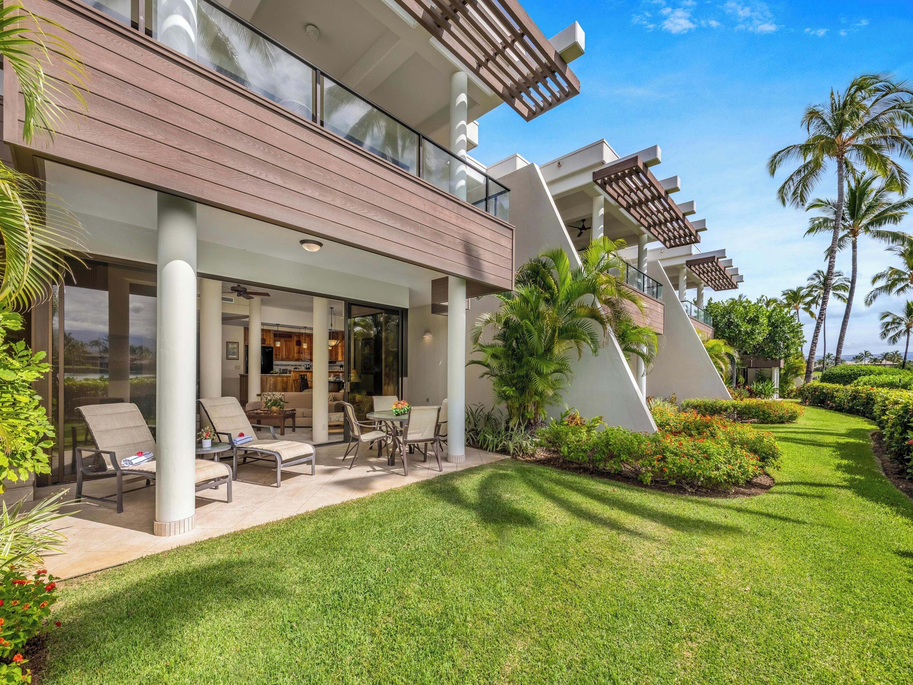 A modern hotel with a covered outdoor seating area, a pool, and lush landscaping.