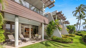 Un hotel moderno con una zona de estar exterior cubierta, piscina y exuberante jardinería.
