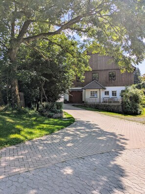 A paved driveway leading to a building with a tiled roof and a small porch.