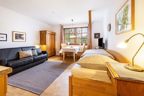 Una stanza con un letto, un divano, un tavolo da pranzo e una finestra con tende.