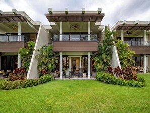 A modern hotel with a symmetrical facade, two-story structure, and a central courtyard with seating and greenery. - Newly Renovated Mauna Lani Point J103 - Modern Style & Comfort On a Golf Course (Kamuela)