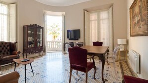 Un soggiorno con tavolo da pranzo, sedie rosse, divano, televisore, mobile contenitore e un grande quadro.