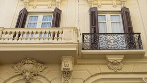 Facciata di un edificio con dettagli architettonici decorativi, tra cui balconi e persiane ornate.