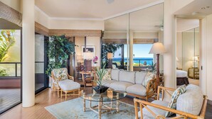 Un salón amplio con un sofá grande, dos sillones, una mesa de centro de vidrio y vista al océano.