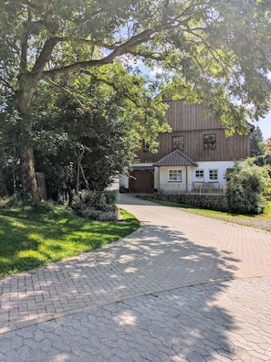 A paved driveway leading to a building with a tiled roof and a small porch.