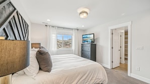 A bedroom with a bed, a dresser, a TV, and a window with a view. - Wasatch Lodge (Heber City)