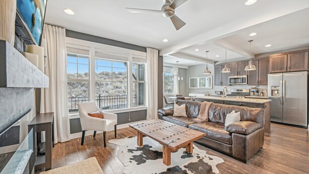 A modern living room with a fireplace, a large window, a sofa, and a dining area. - Wasatch Lodge (Heber City)