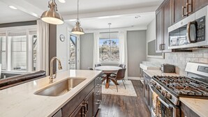 A modern kitchen with a large island, stainless steel appliances, and a dining area with a view. - Wasatch Lodge (Heber City)