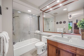 Une salle de bain moderne avec une douche à parois de verre, des toilettes blanches et un meuble-lavabo avec un miroir.