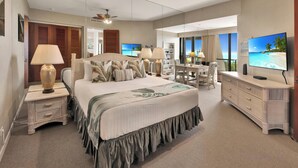 A spacious hotel room with a large bed, a desk, a chair, a TV, and a ceiling fan. - Discounted Golf Rates! Mauna Lani Point E203 w/Ocean Views - CoralTree Managed (Kamuela)