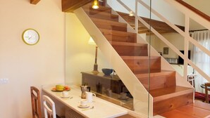 A kitchen with a wooden staircase, a clock, and a dining area with a table and chairs. - Casa Fresno country lodging for up to 5 people near Salamanca (ALMENARA DE TORMES)