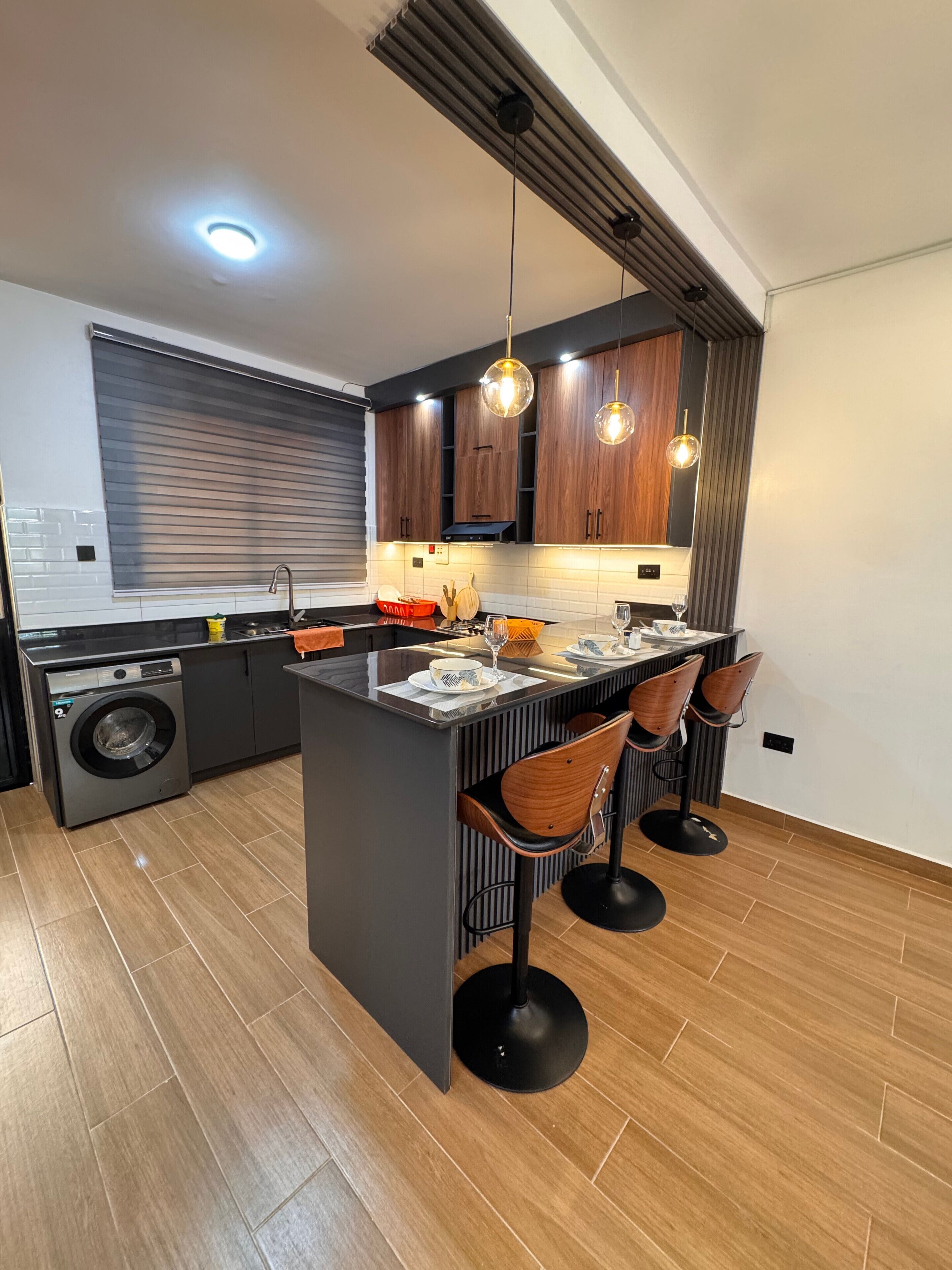 Una cucina moderna con isola centrale, mobili in legno e luci a sospensione.