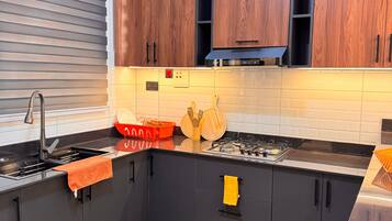 Una cucina moderna con mobili scuri, un lavandino in acciaio inossidabile e un tappeto giallo decorato.
