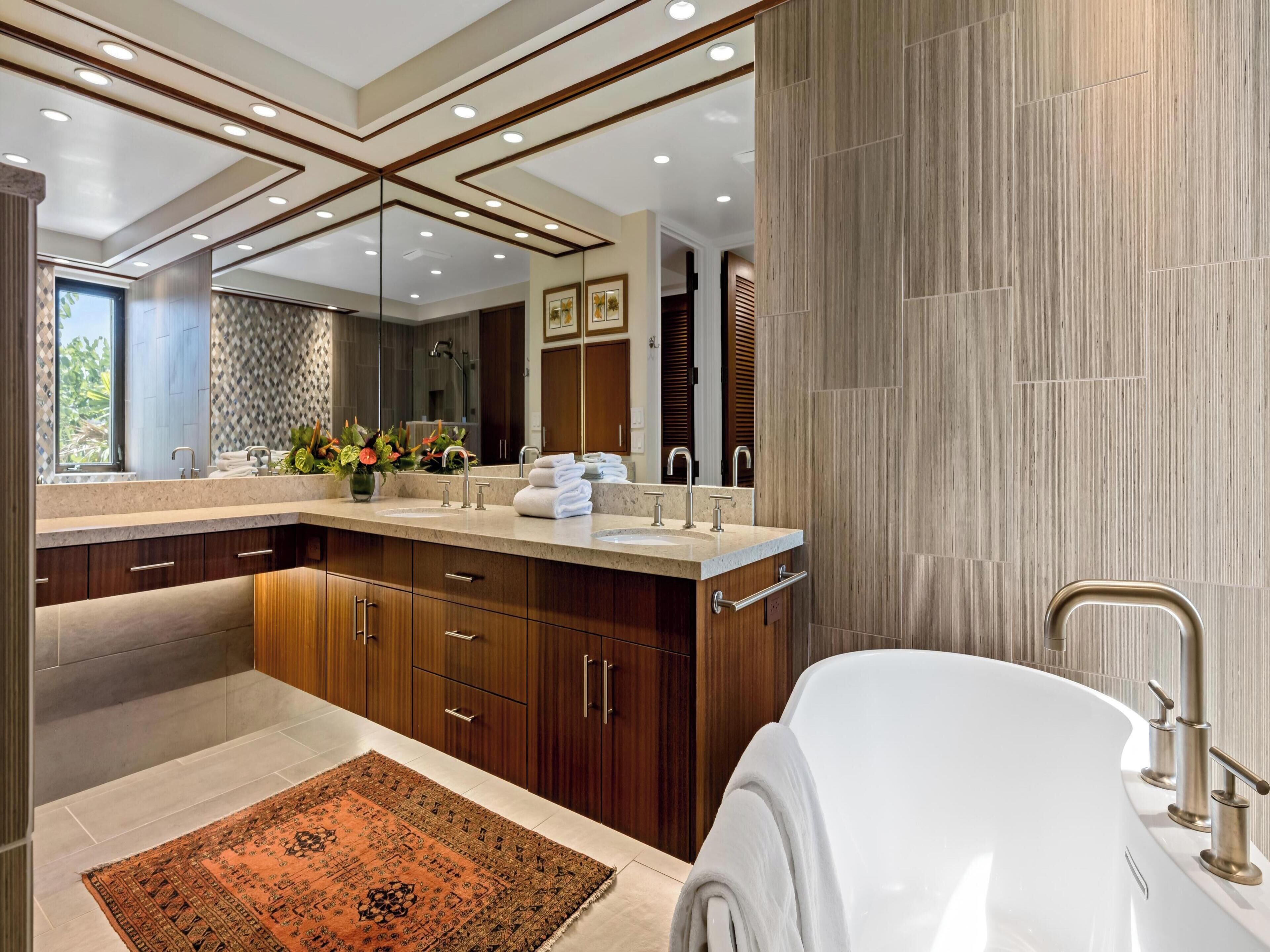 A modern bathroom with a double sink vanity, a large mirror, and a freestanding bathtub.