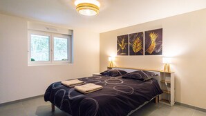 A bedroom with a bed, two bedside tables, a window, and three wall-mounted artworks. - Private 3-seater Jacuzzi, garden, air conditioning & parking - Dieulouard A31 (Dieulouard)